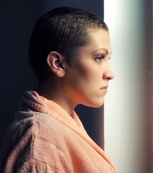 female young person wearing orange and looking out of the window. image of support for cancer patients