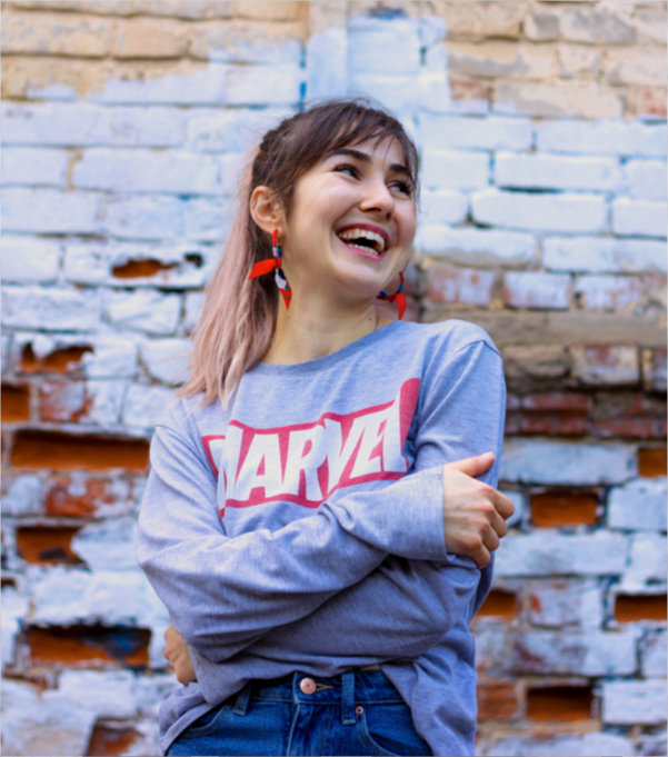 girl laughing and looking to the side. she is wearing a grey marvel jumper