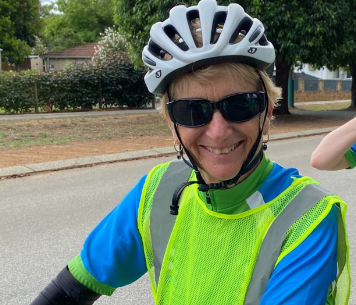 canteen volunteer jenny wearing a helmet and hi vis while riding a bike