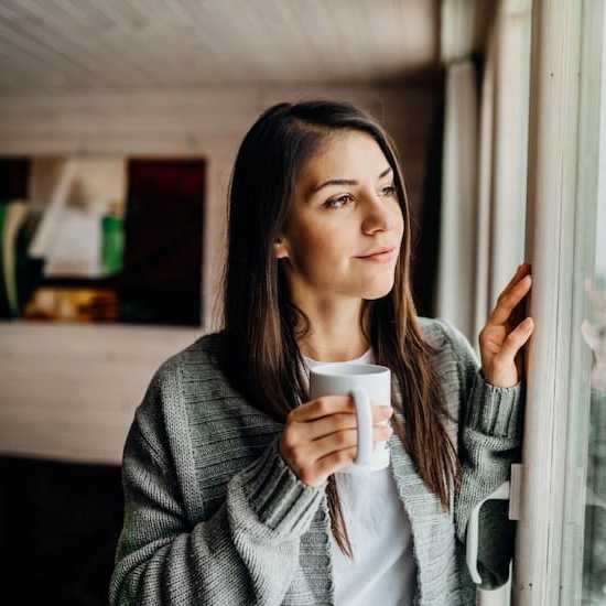 Young woman holding cup looking out window