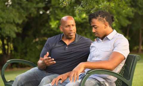 Father and son discussing cancer in a park