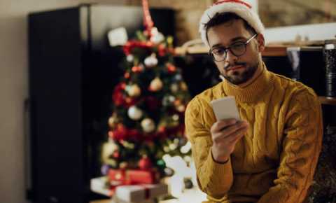 young person wearing a santa hat and looking at their phone