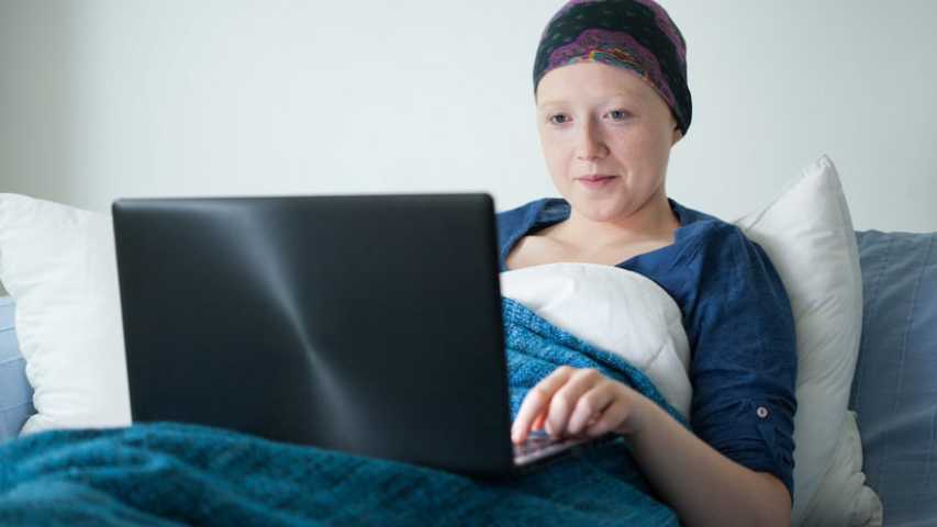 Young woman in hospital bed doing school work