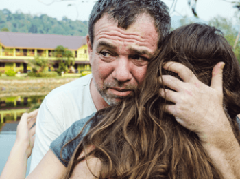 Upset father hugging daughter