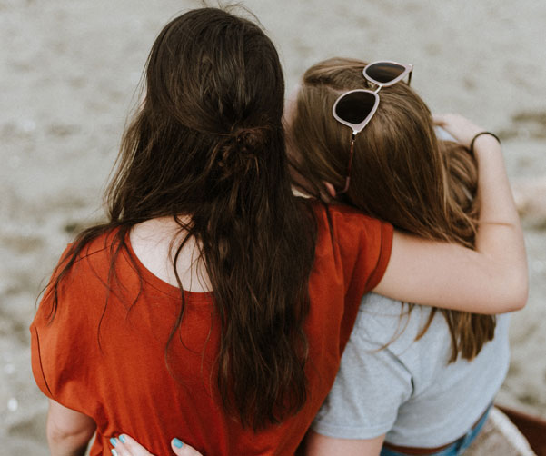 Two siblings hugging at the beach - canteen family cancer support