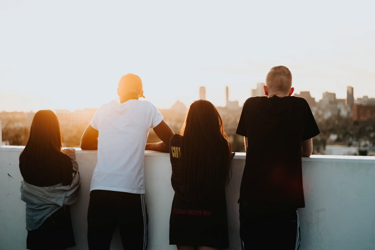 four friends looking into the sunset from a balcony