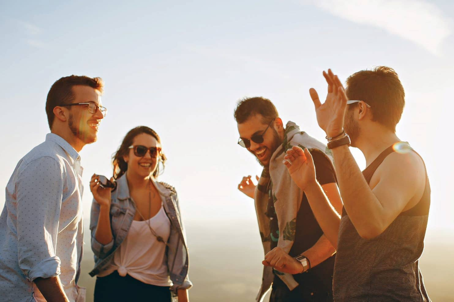 four friends dancing during sunset