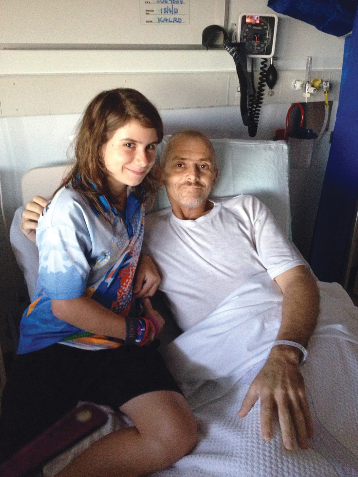 a young girl named Chloe sitting with her father who has cancer in a hospital bed