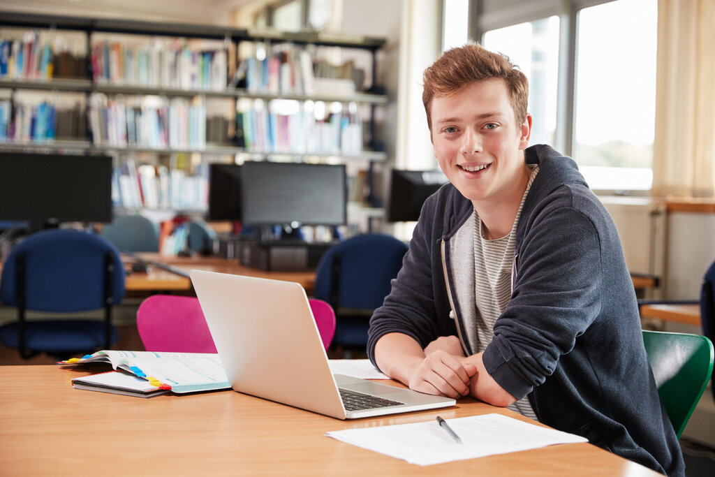 a young man sitting at a desk with a laptop open