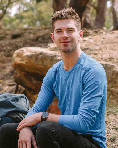 Image of Daniel, a young person who has benefited from Canteen's free cancer support services, sitting in a woodland smiling